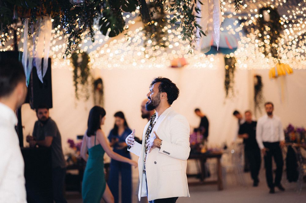 Reception celebration under twinkling lights with guests dancing and mingling.