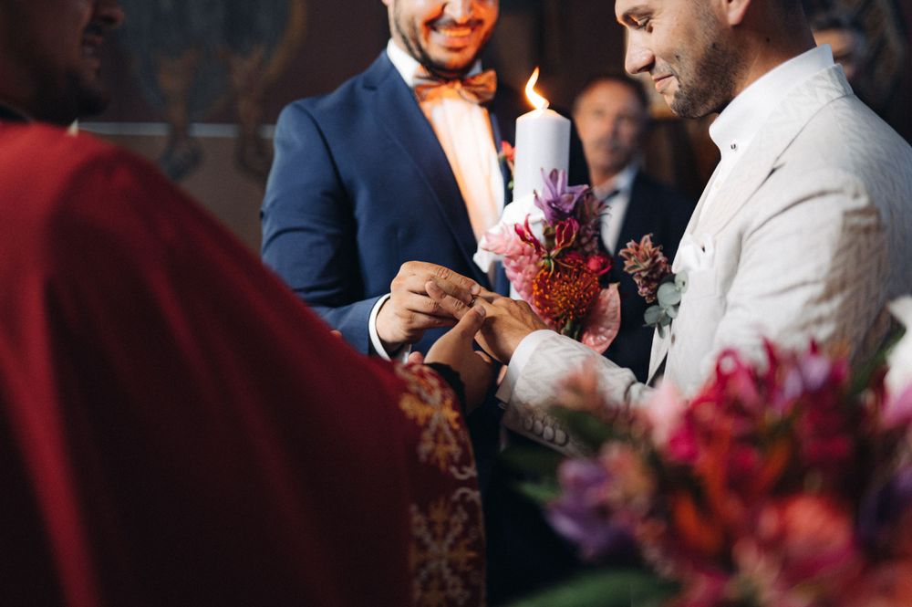 Close-up of candle lighting ritual during wedding ceremony with purple floral accents.