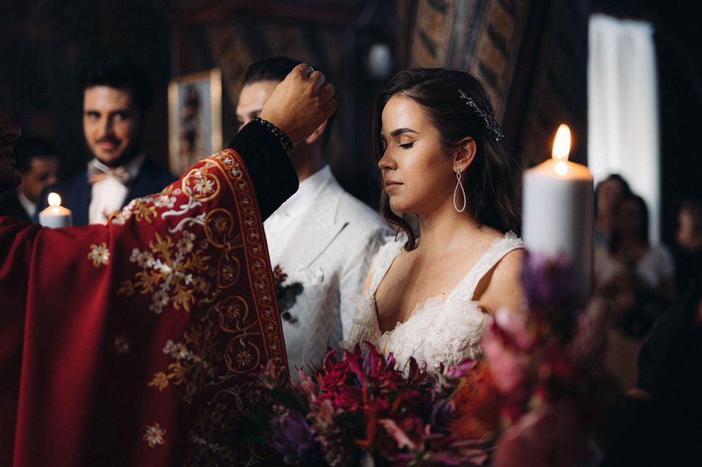 A solemn wedding ceremony moment with candles and purple flowers in the foreground.