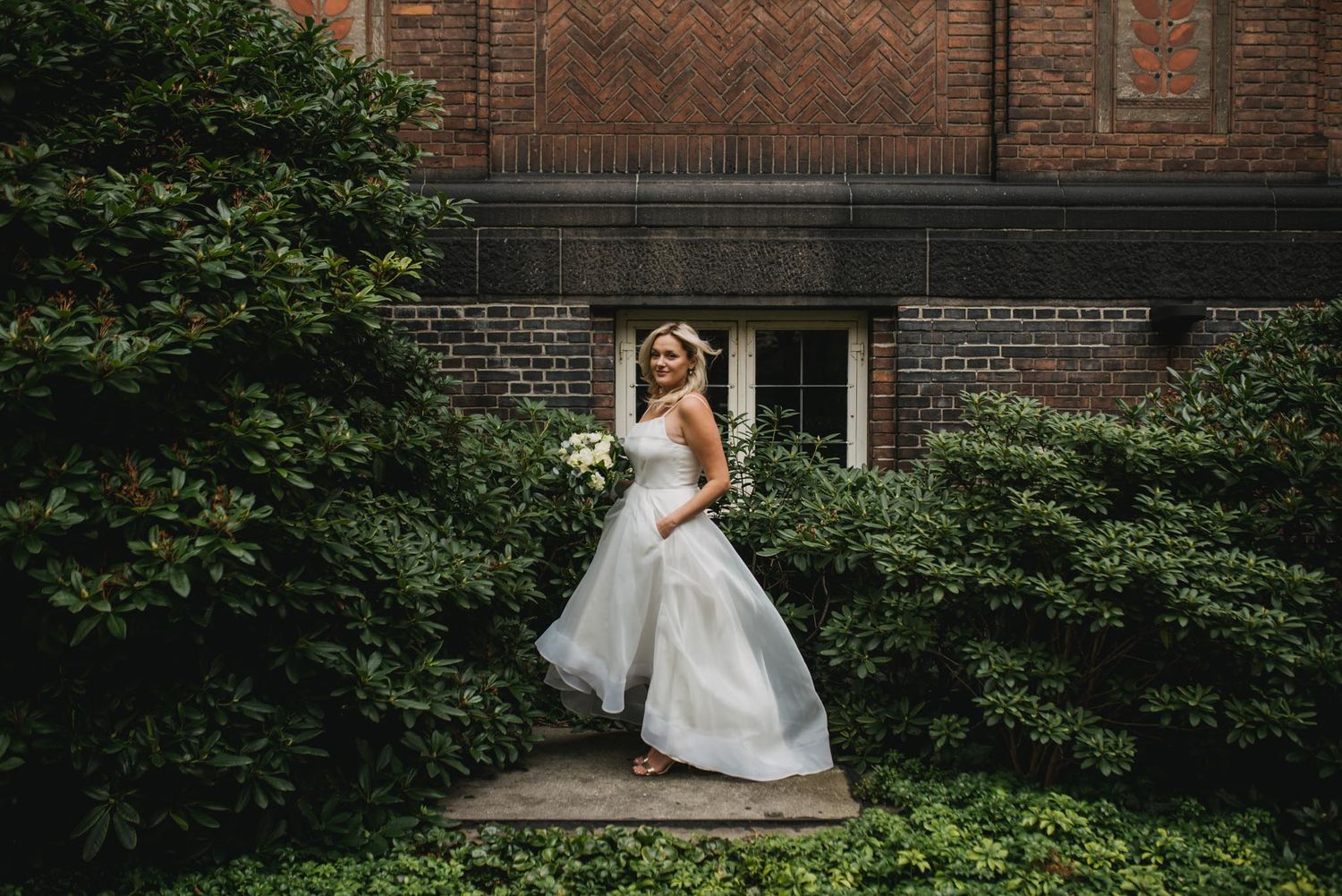 A bride on her wedding day posing in the garden at Copenhagen City Hall