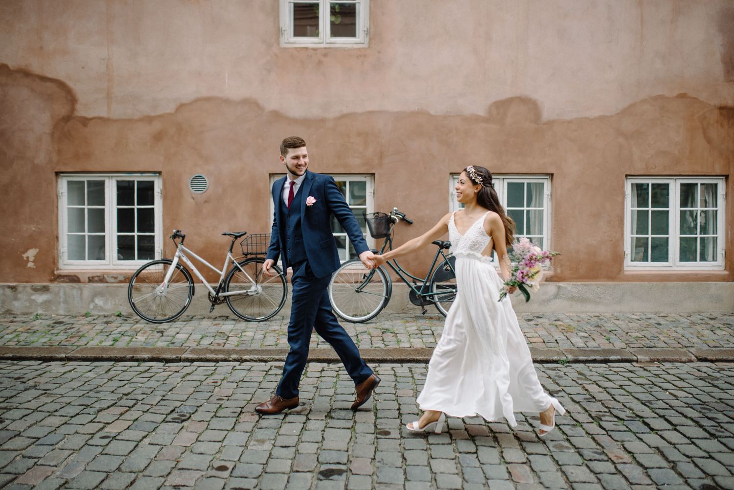 A couple on their wedding day running around Christianshavn neighborhood in Copenghagen