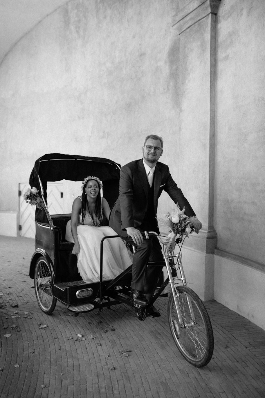 A couple on their wedding day riding a christiania bike in Christiansborg Palace area in Copenhagen