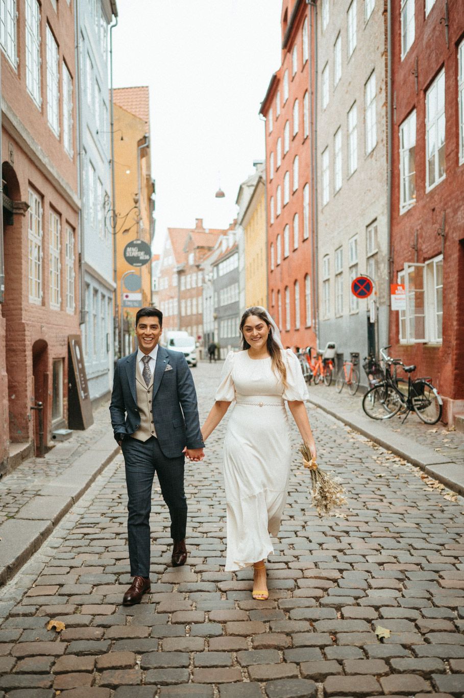 A couple on their wedding day walking on Magstræde in Copenhagen
