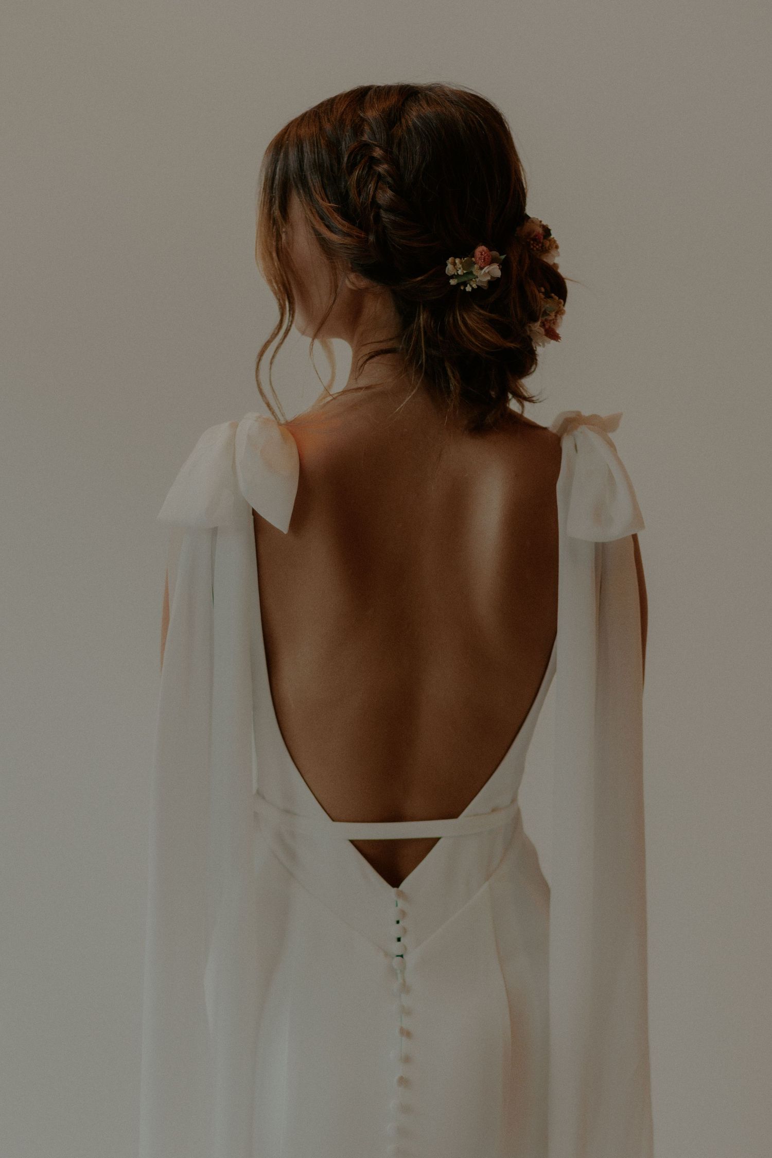 Detailed back view of wedding gown showing intricate braided hairstyle and button closure.