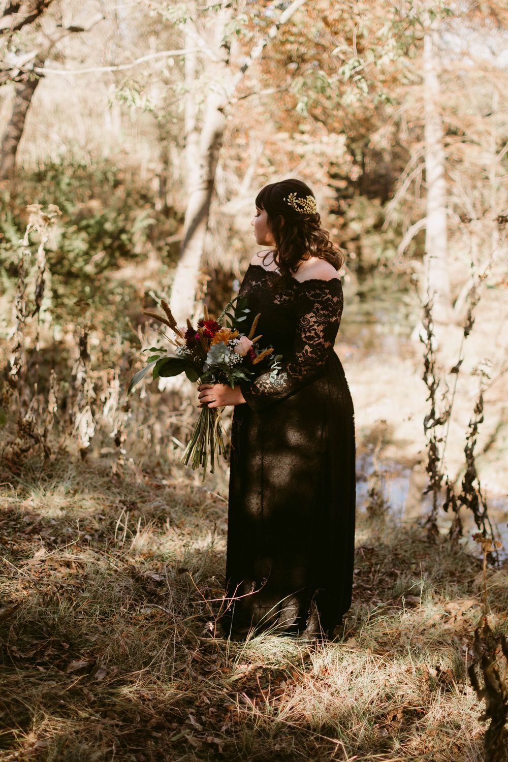 Ethereal forest scene with long black lace dress and autumn flowers.