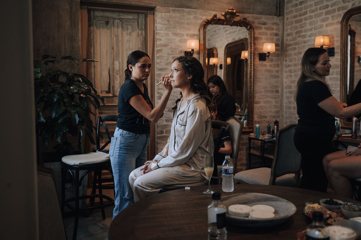 Getting ready scene in a rustic brick room with warm lighting and vintage decor.