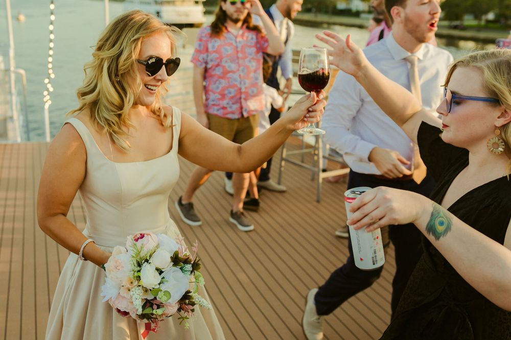 epic picture of bride with bouquet and drink at hand with sunglasses
