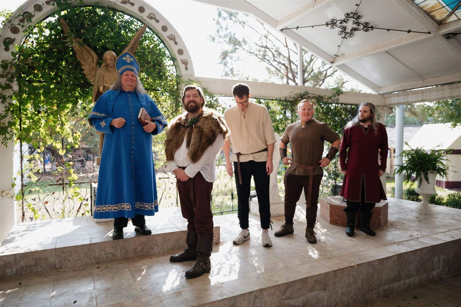 Performers in medieval attire stand on an elevated platform during a renaissance fair event.