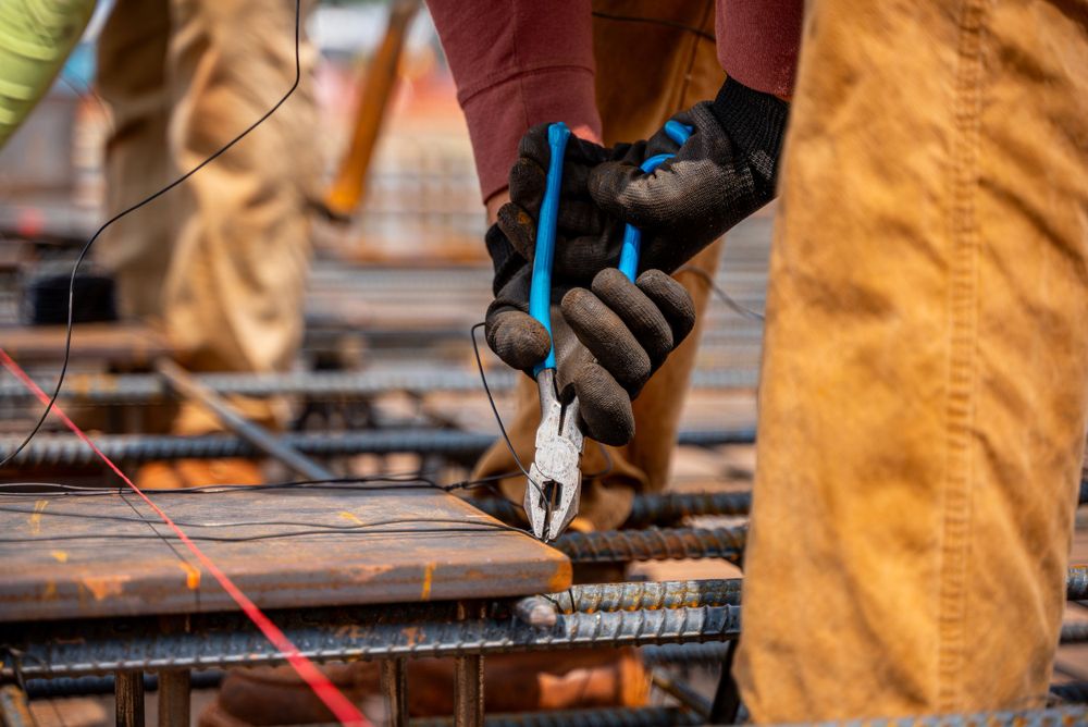 Construction worker using pliers on rebar at construction site.
