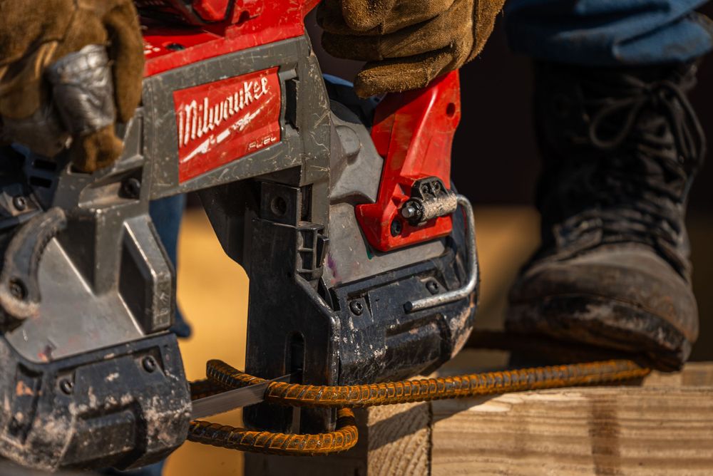 Milwaukee power tool being used to cut construction materials on wooden surface.