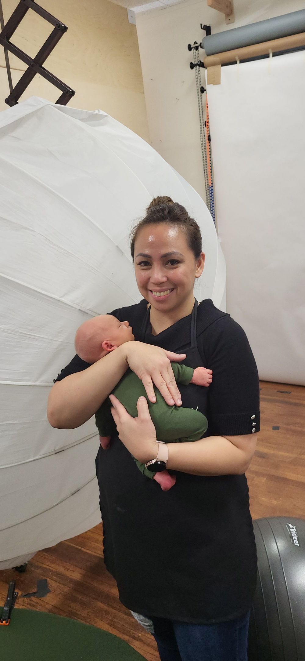 Photographer in a black shirt working with a baby in a studio setting.
