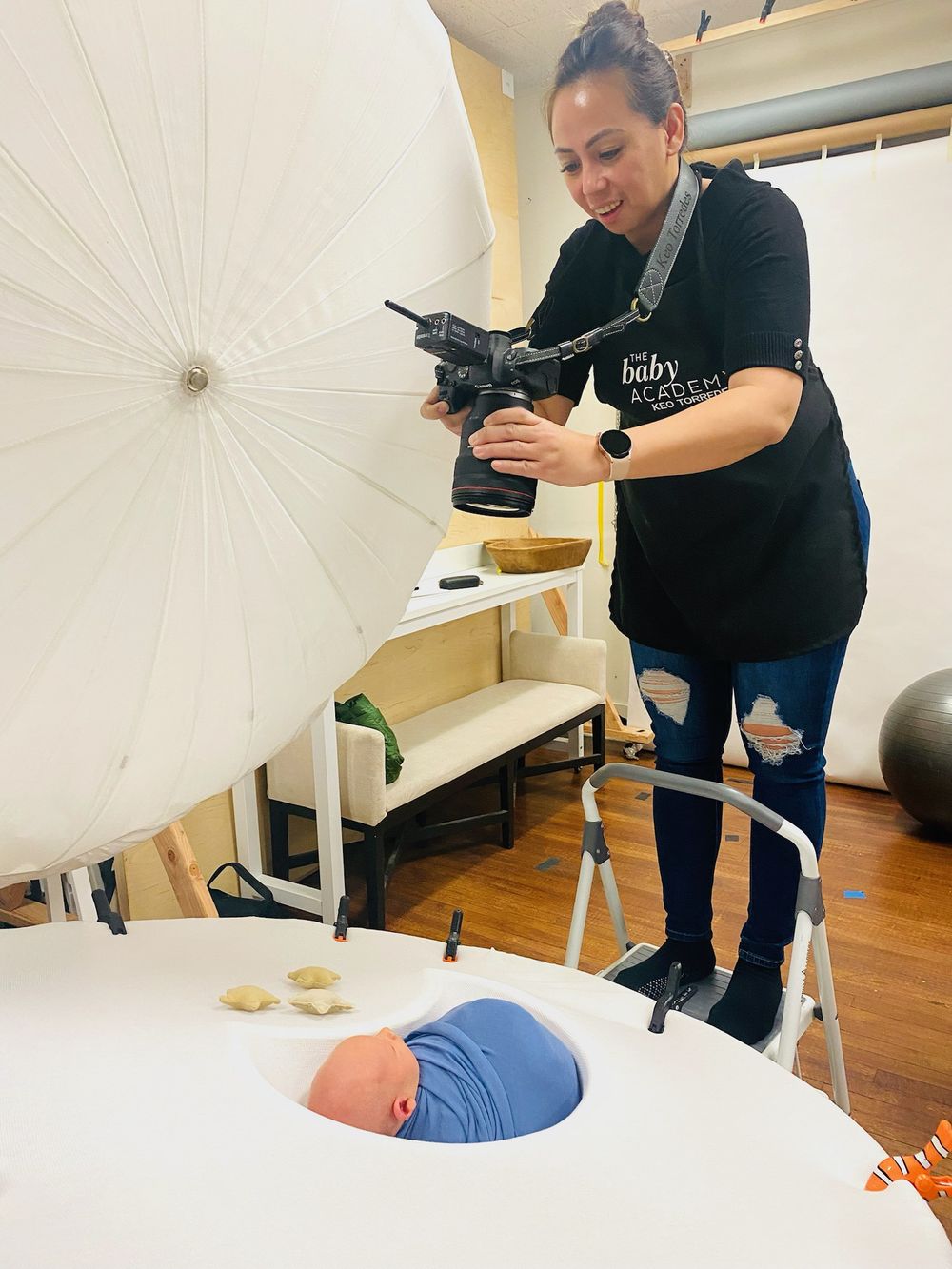 Photographer capturing overhead shots of a newborn with professional studio lighting equipment.