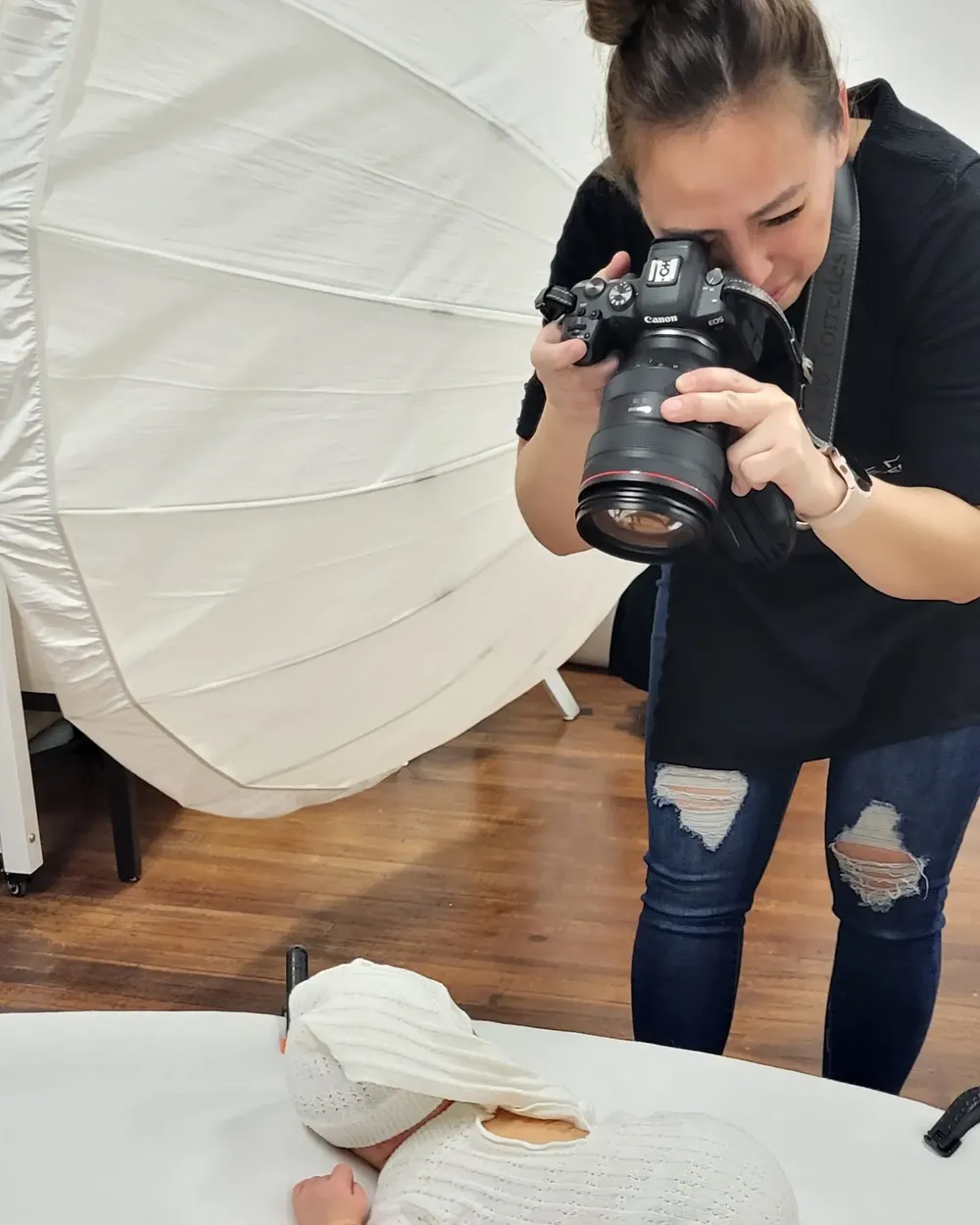 Photographer taking overhead shots with professional camera in a studio with white backdrop.