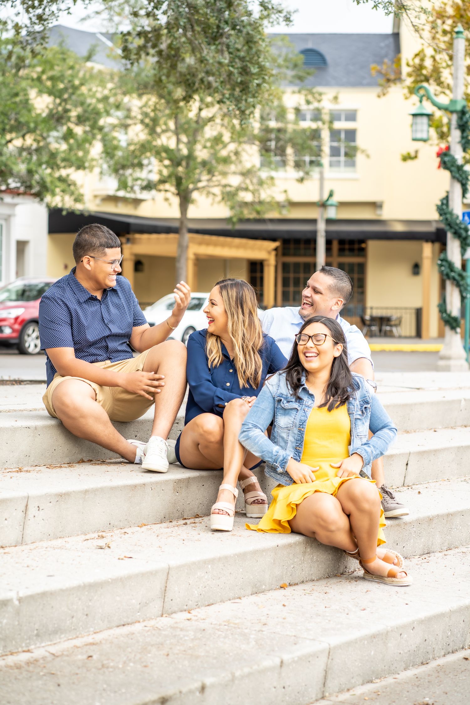 Four friends sitting casually on concrete steps having an animated conversation outdoors.