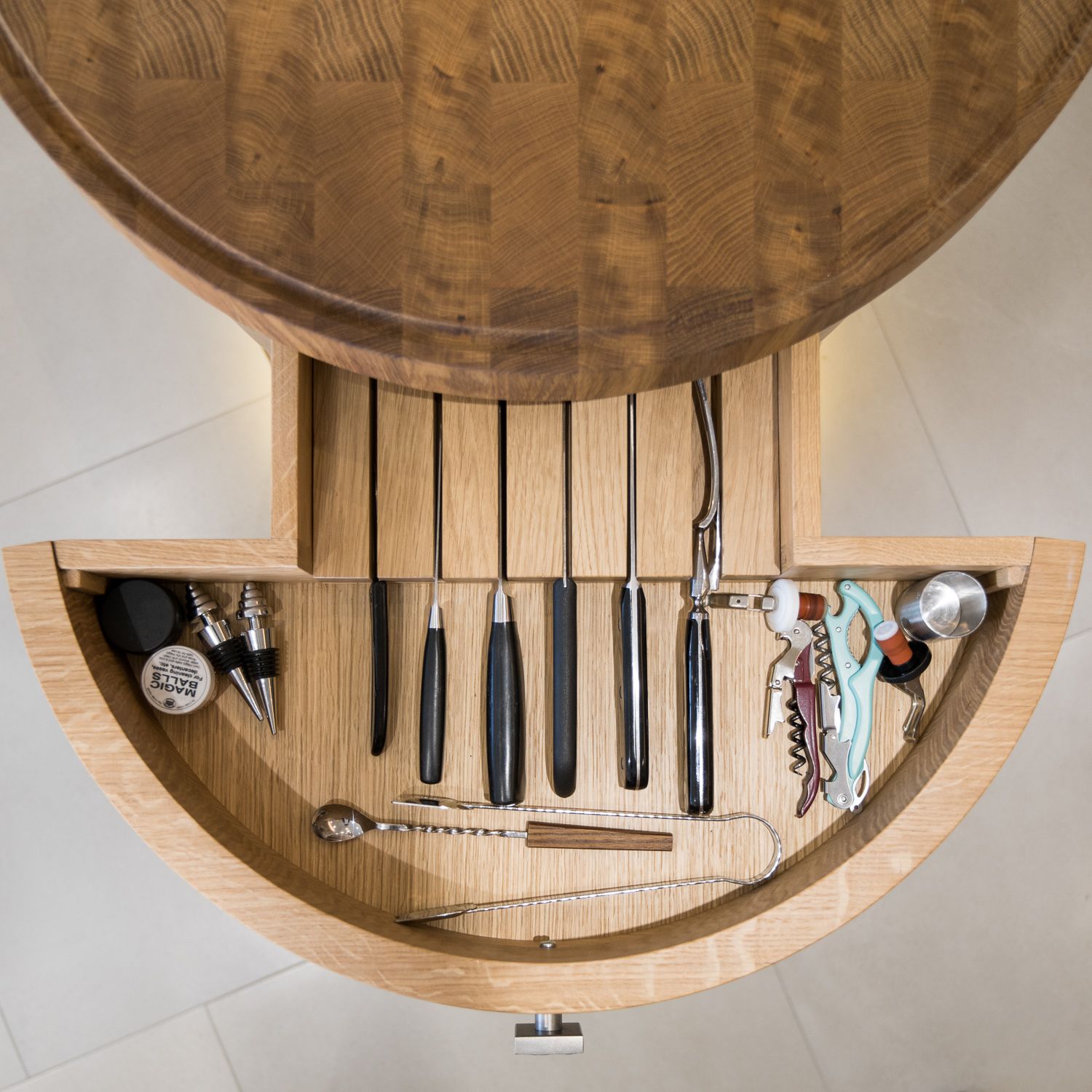 Overhead view of a wooden jewellery storage drawer with knife slots and compartments for organising accessories.