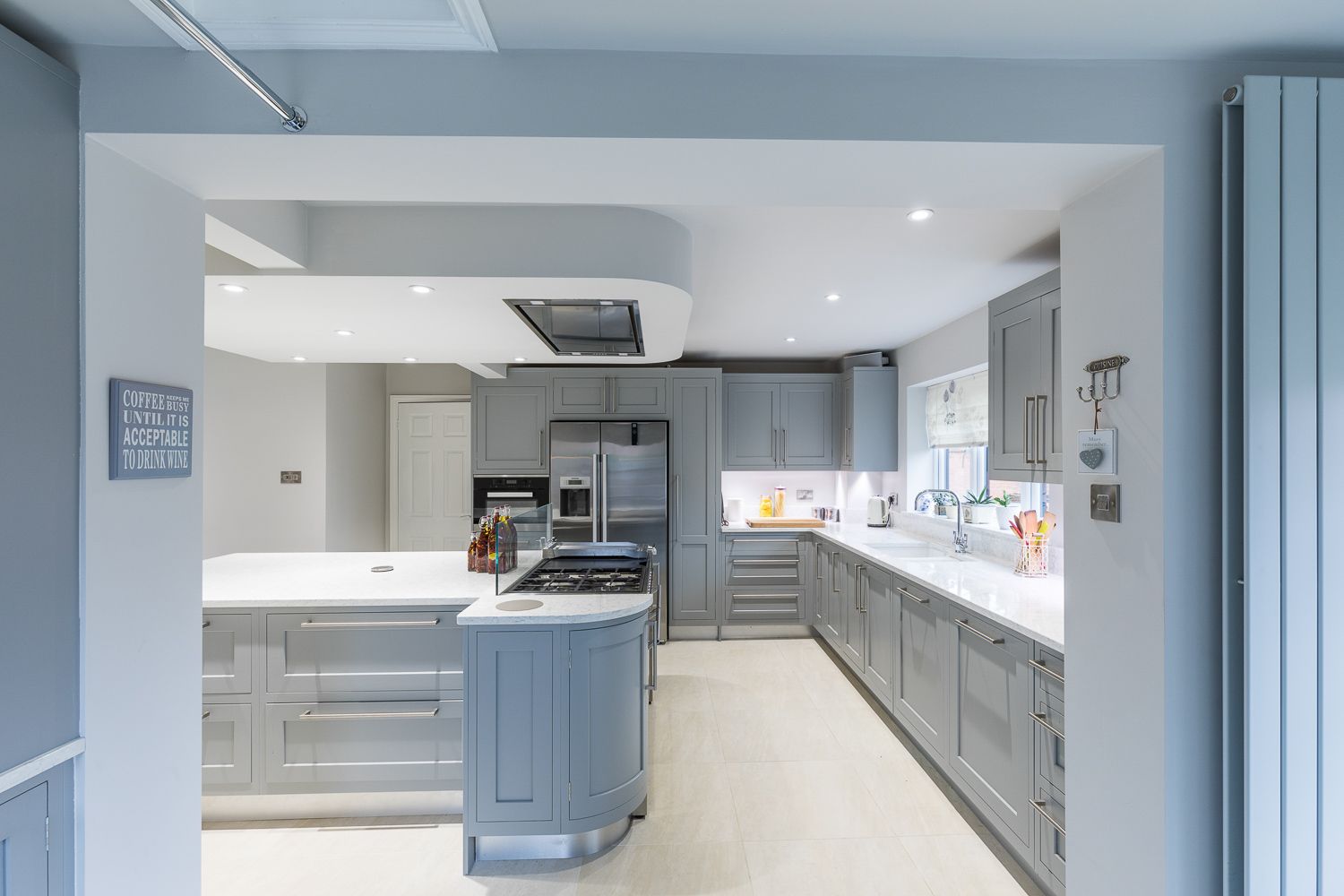 Modern grey and white kitchen with sleek cabinets, quartz countertops, and stainless steel appliances in an L-shaped layout.
