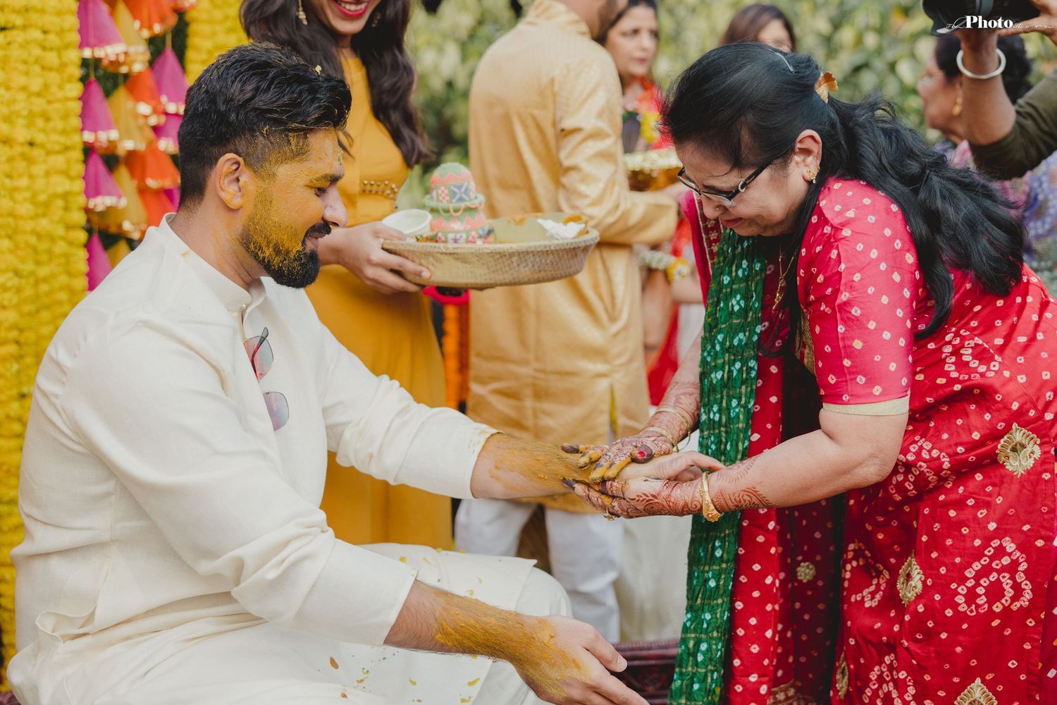Joyful celebration at an outdoor Indian wedding ceremony with vibrant yellow and red decor.