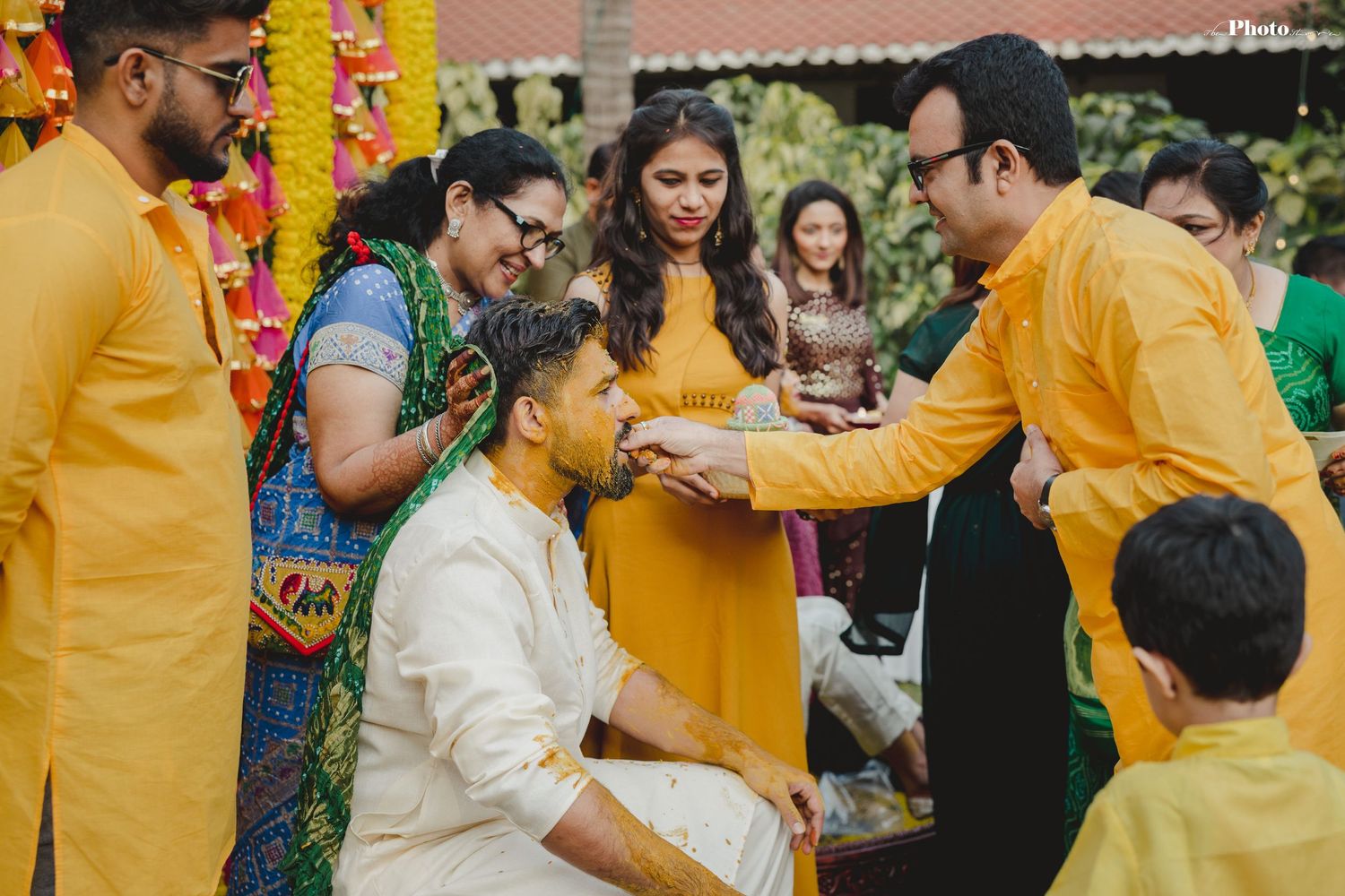 Pre-wedding ceremony with guests in yellow and white attire participating in cultural traditions.