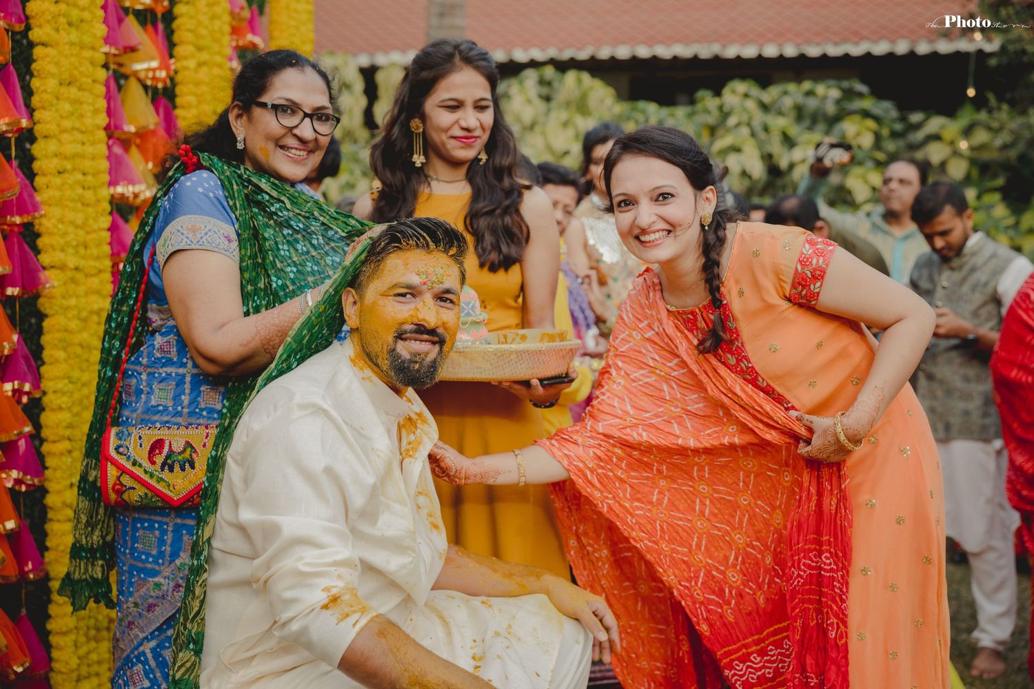 Festive gathering at an outdoor Haldi ceremony with decorative floral arrangements and bright fabrics.