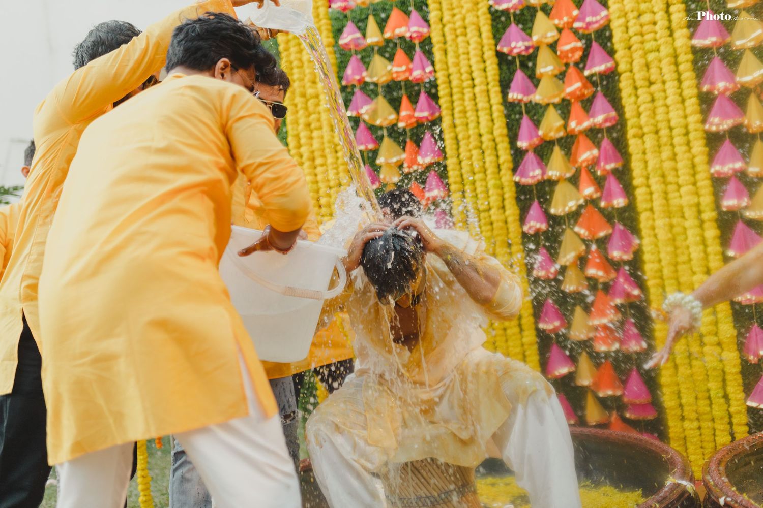 Group celebrating Haldi ceremony with yellow decorations and traditional flower garlands.