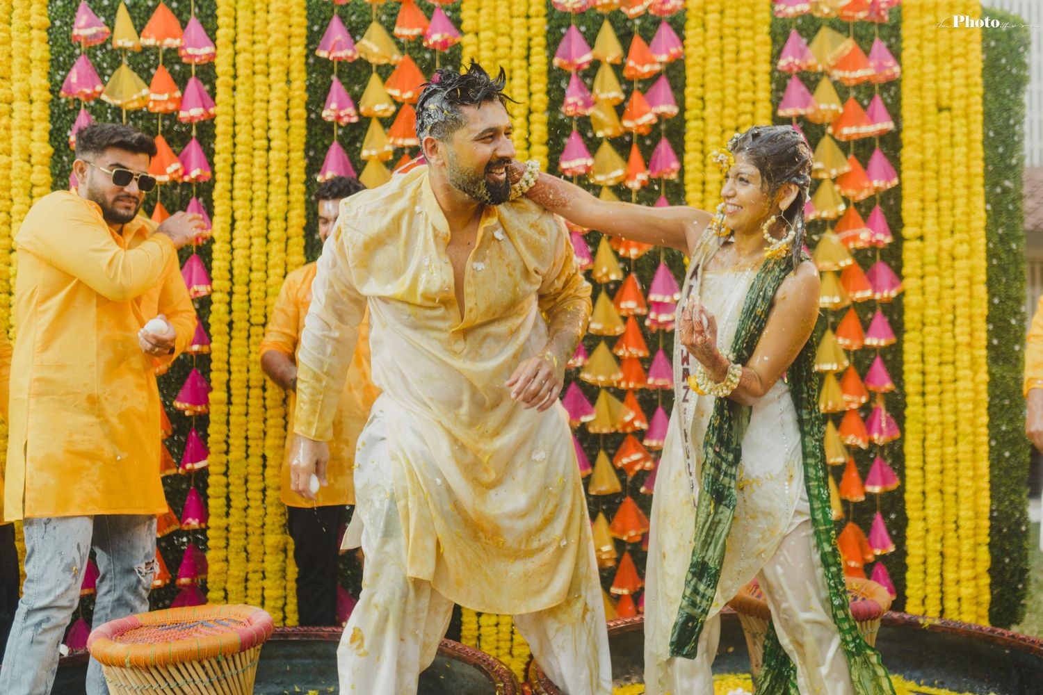 Traditional Indian pre-wedding celebration with yellow marigold decorations and pink paper ornaments.