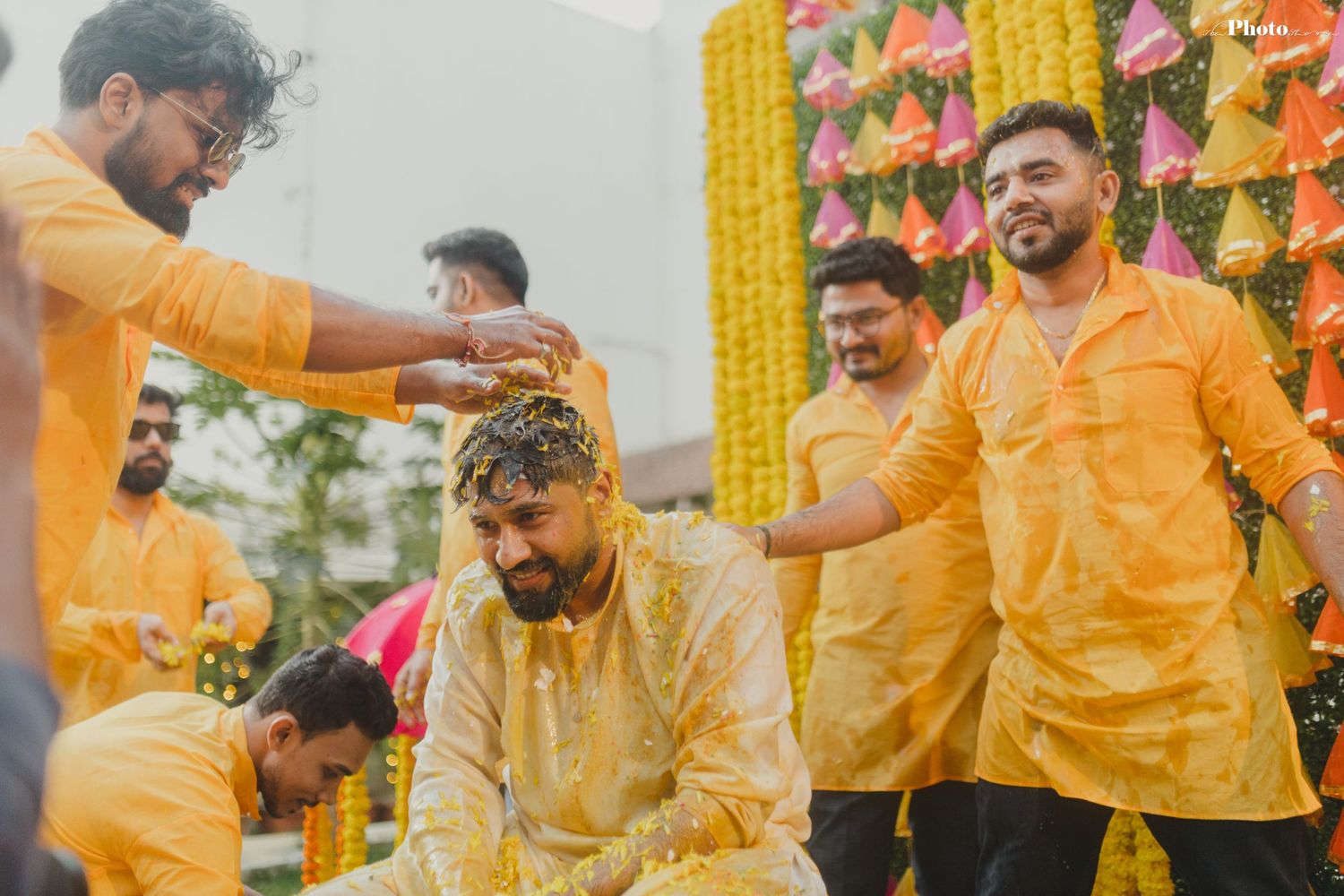 Festive gathering with people wearing yellow outfits against floral backdrop.