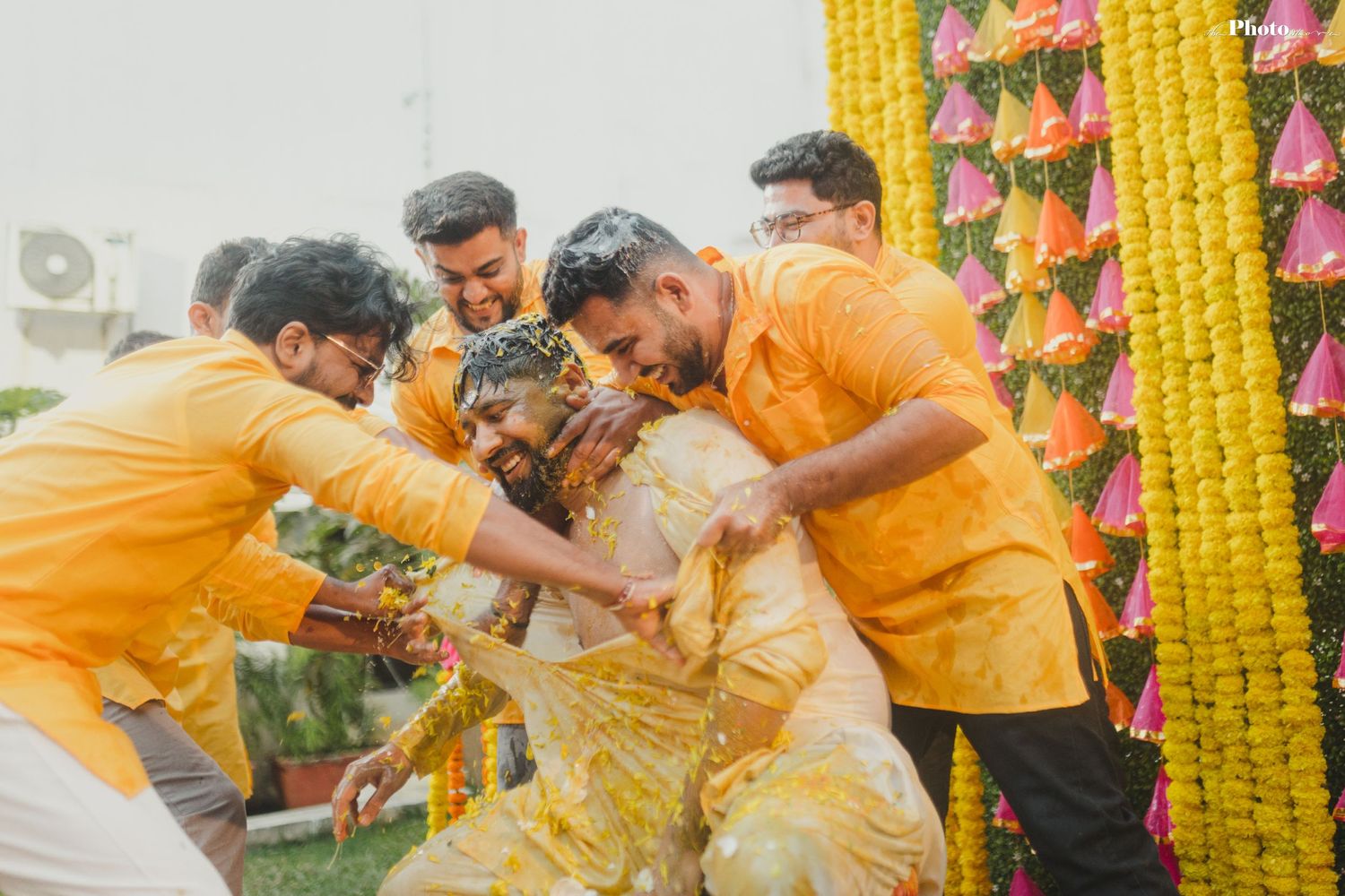 Celebrants in yellow attire participating in traditional Haldi ceremony festivities.