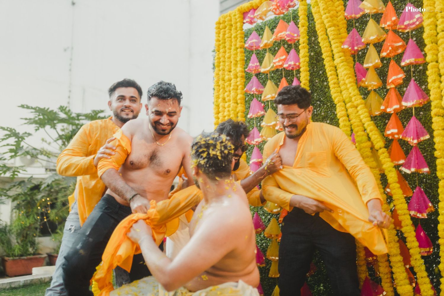Outdoor celebration scene with marigold garlands and pink decorative elements.