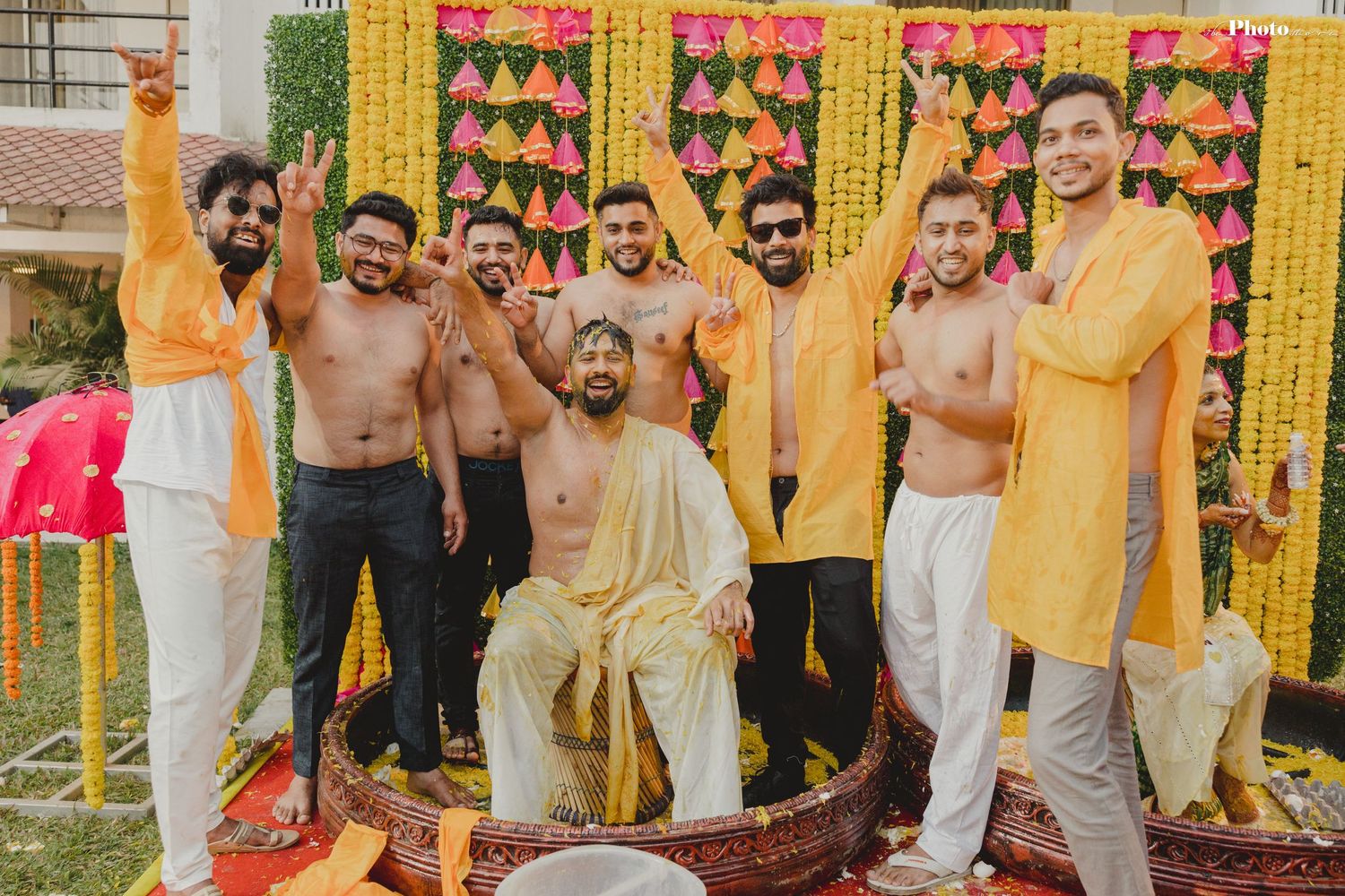 Festive wedding ceremony backdrop with yellow marigold garlands and pink floral decorations creating a vibrant atmosphere.