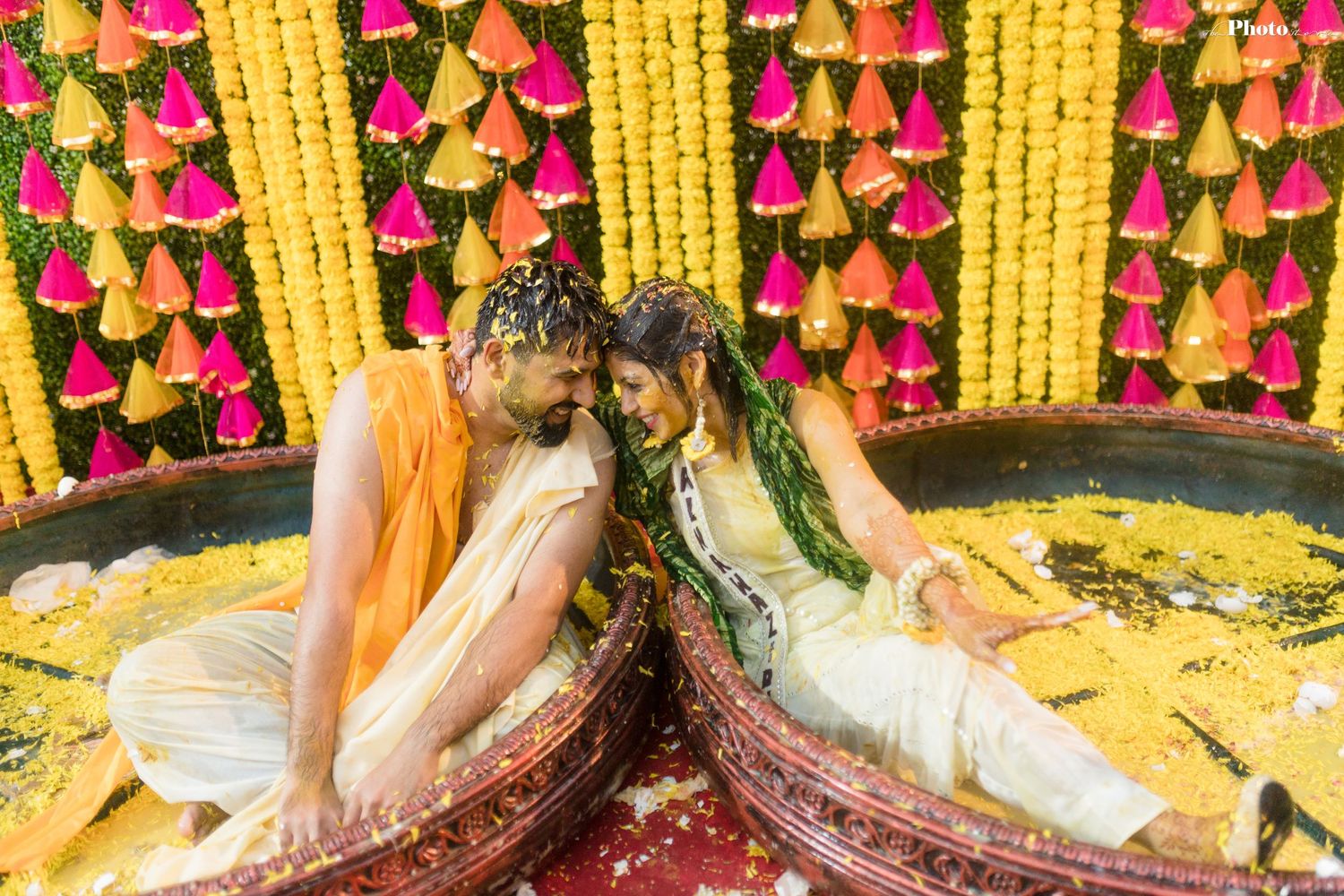 Traditional Indian wedding decor featuring hanging yellow marigold strands and pink flower arrangements.