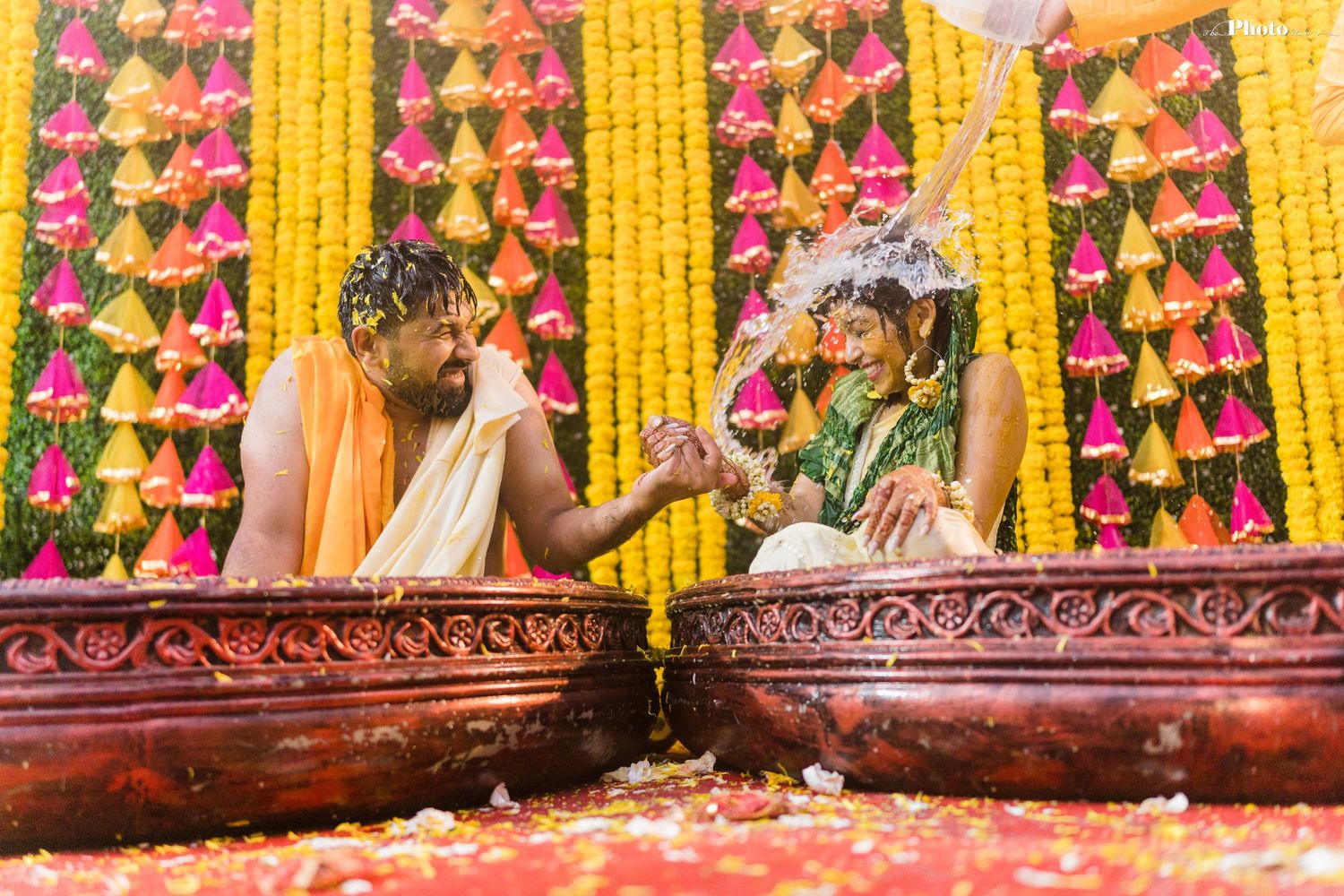 Elegant wedding mandap with cascading yellow marigold strings and pink flower decorations.