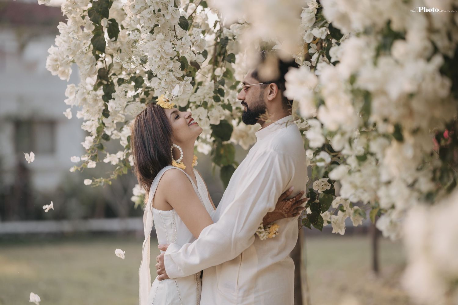 Romantic portrait session among cascading white flower blossoms in soft afternoon light.