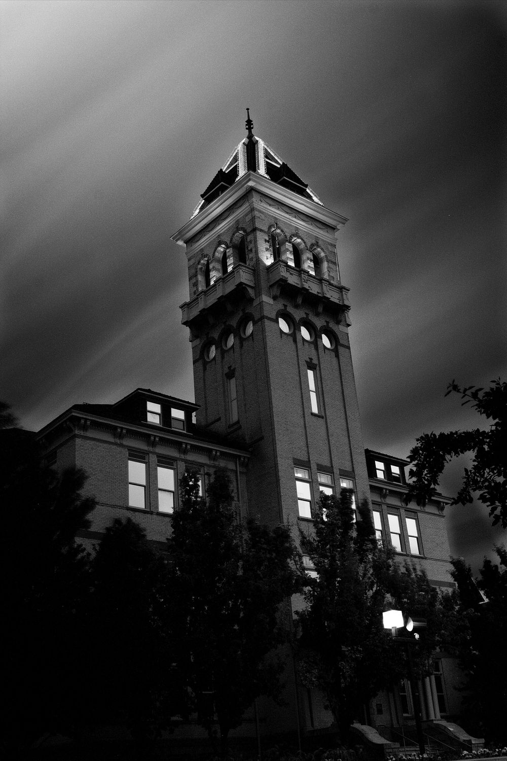 Gothic clock tower of historic building against dark stormy sky in black and white.