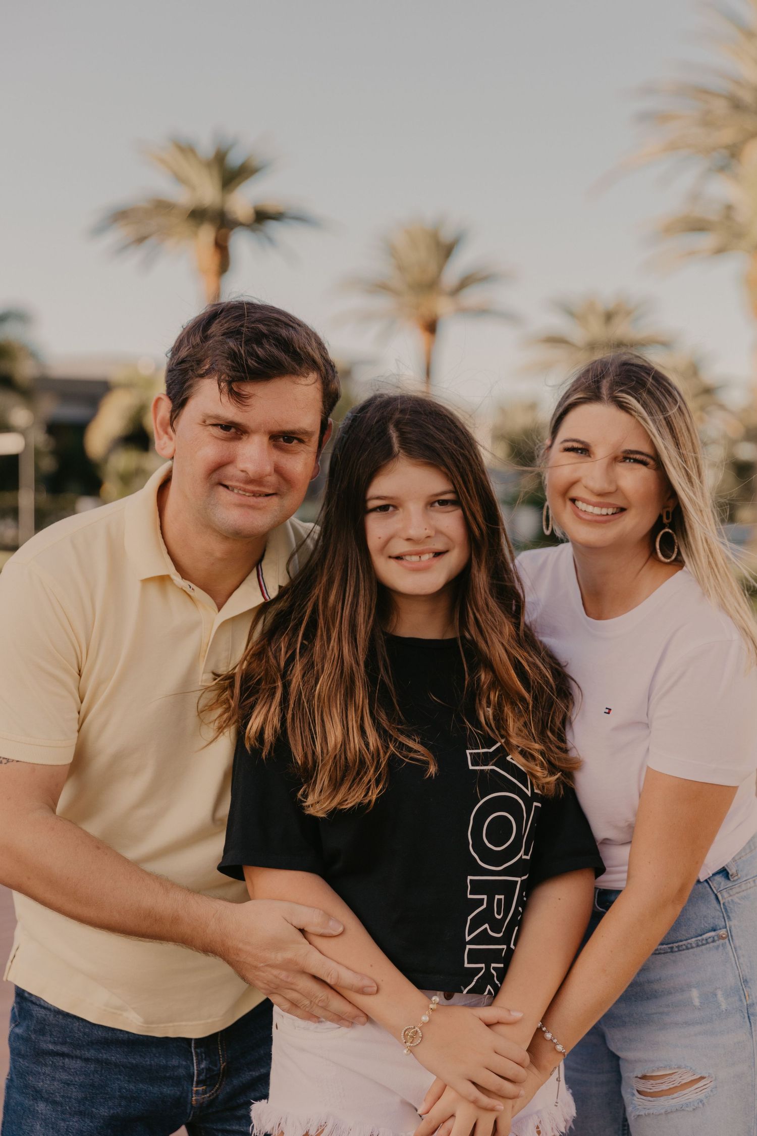 Family portrait at sunset with palm trees in background.