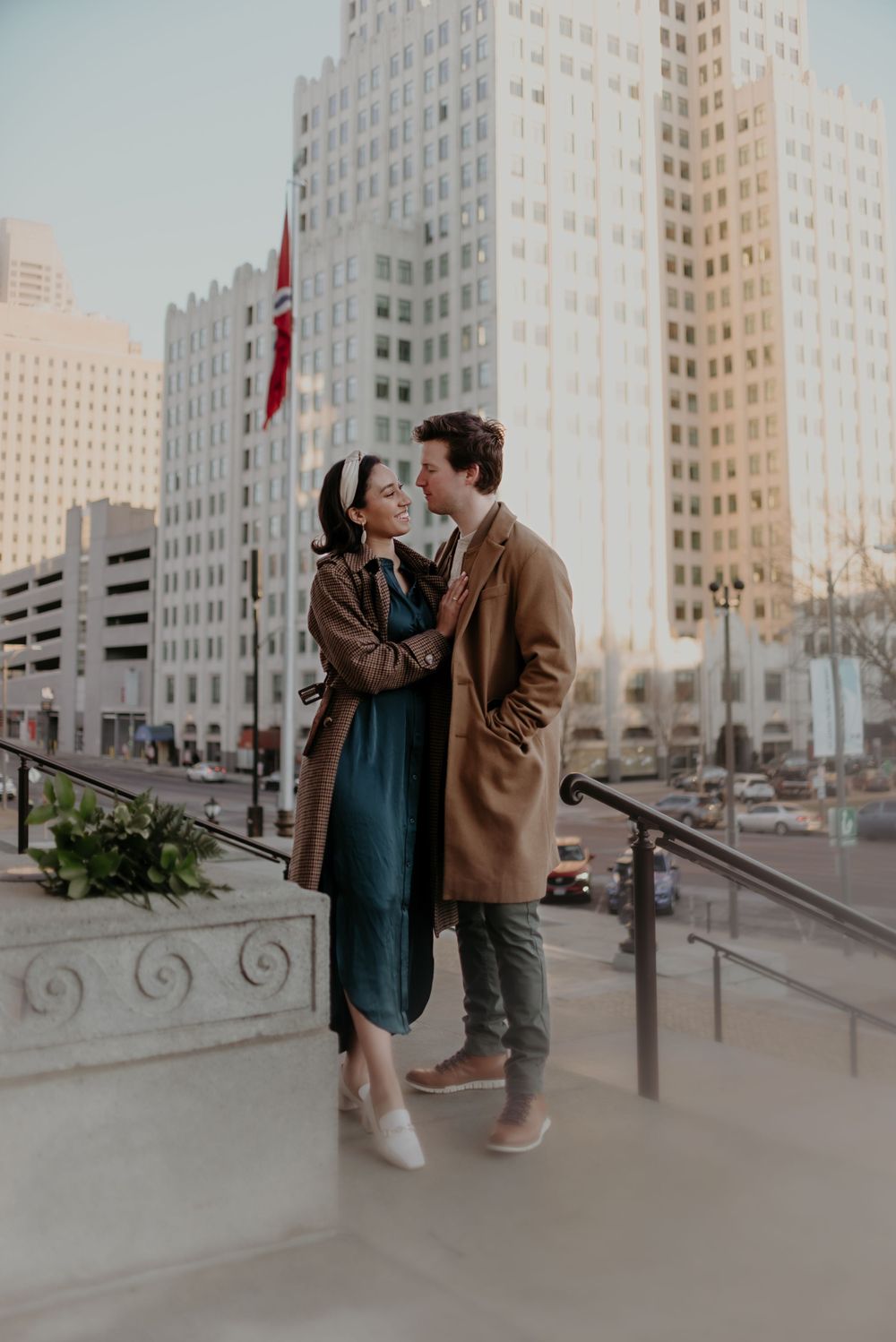 A couple shares a romantic moment against a backdrop of tall city buildings and a Canadian flag.