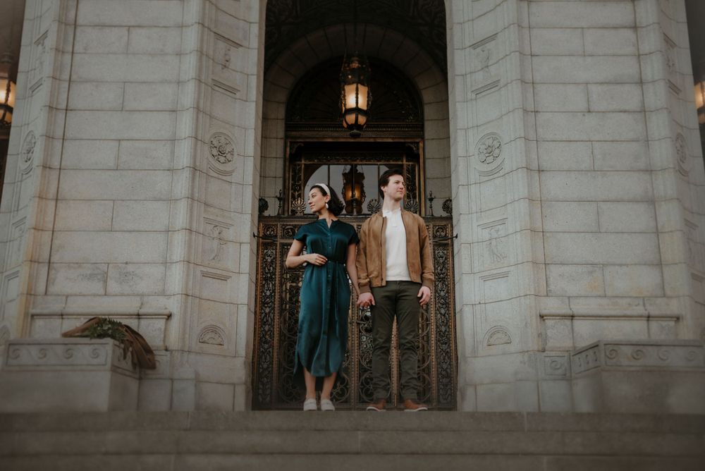 A couple poses together in an ornate archway of a historic building.