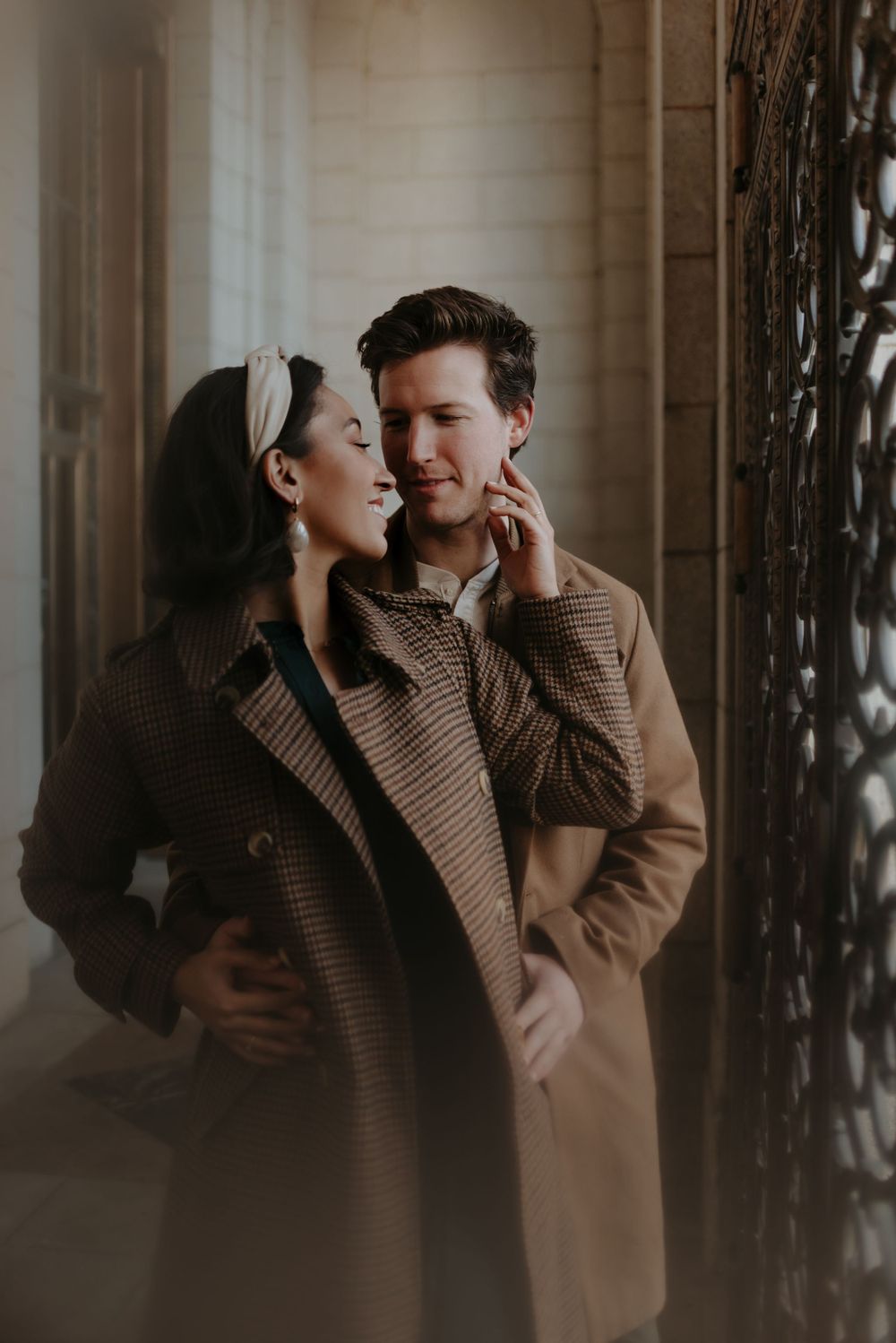 A couple embraces in warm light against a classical architectural backdrop.