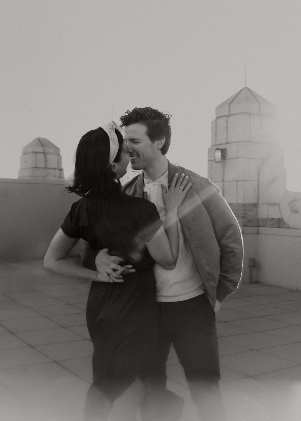 Black and white rooftop romance with architectural towers in background.