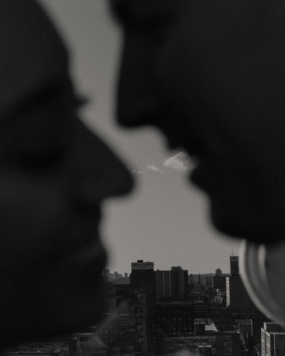 Silhouetted figures against city skyline in black and white photograph.