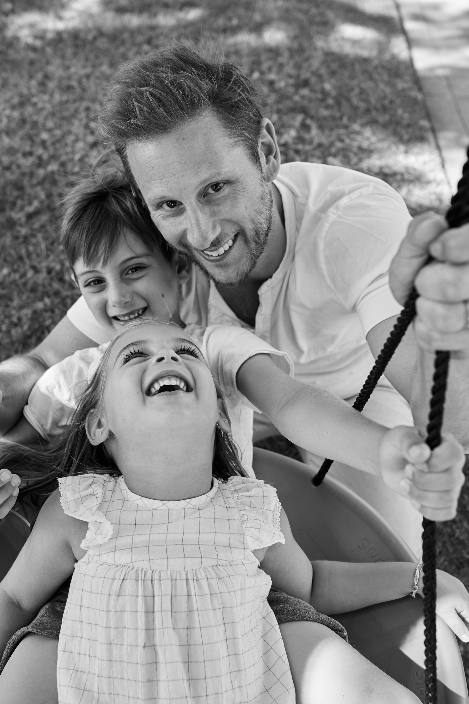 A joyful black and white family moment on a swing outdoors.