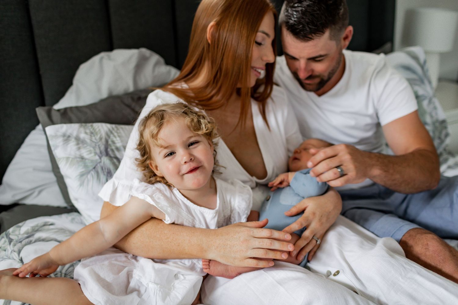 Heartwarming family scene with toddler and newborn on bed.