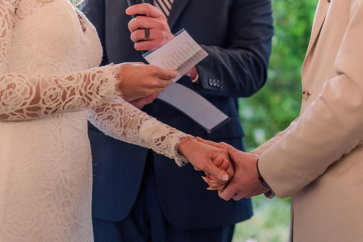 Bride and groom holding hands during wedding ceremony close up photograph