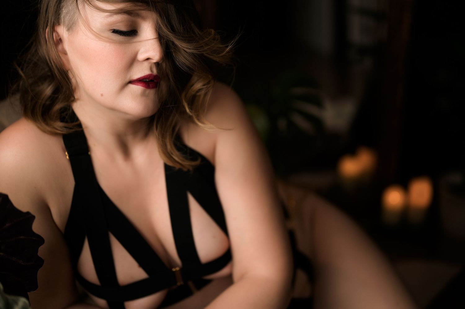 Moody boudoir photo featuring black strappy lingerie in low light setting.