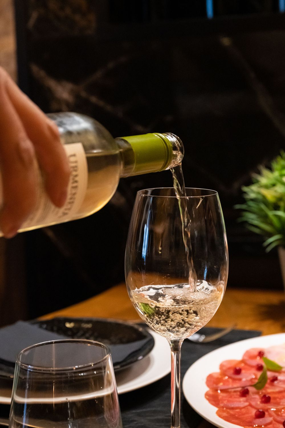 Wine being poured into glasses beside a beautifully presented appetizer plate.