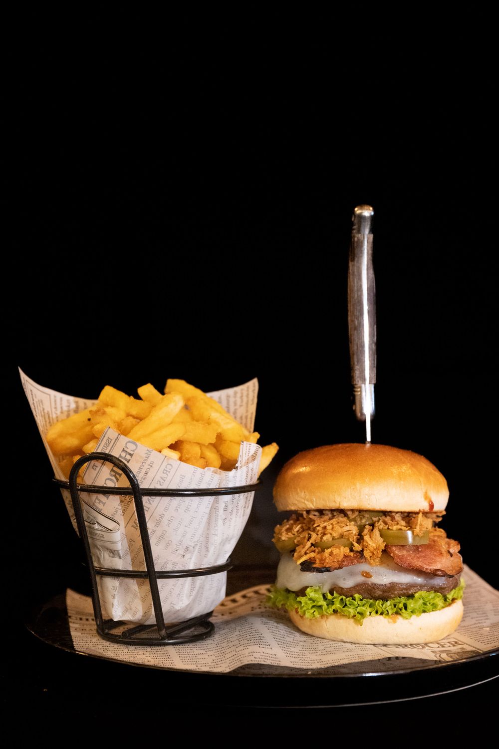 Classic hamburgers and french fries served on wooden boards against a dark background.