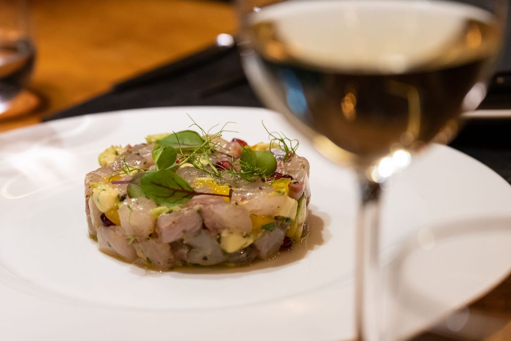 Close-up of elegantly plated gourmet dishes on a wooden restaurant table.