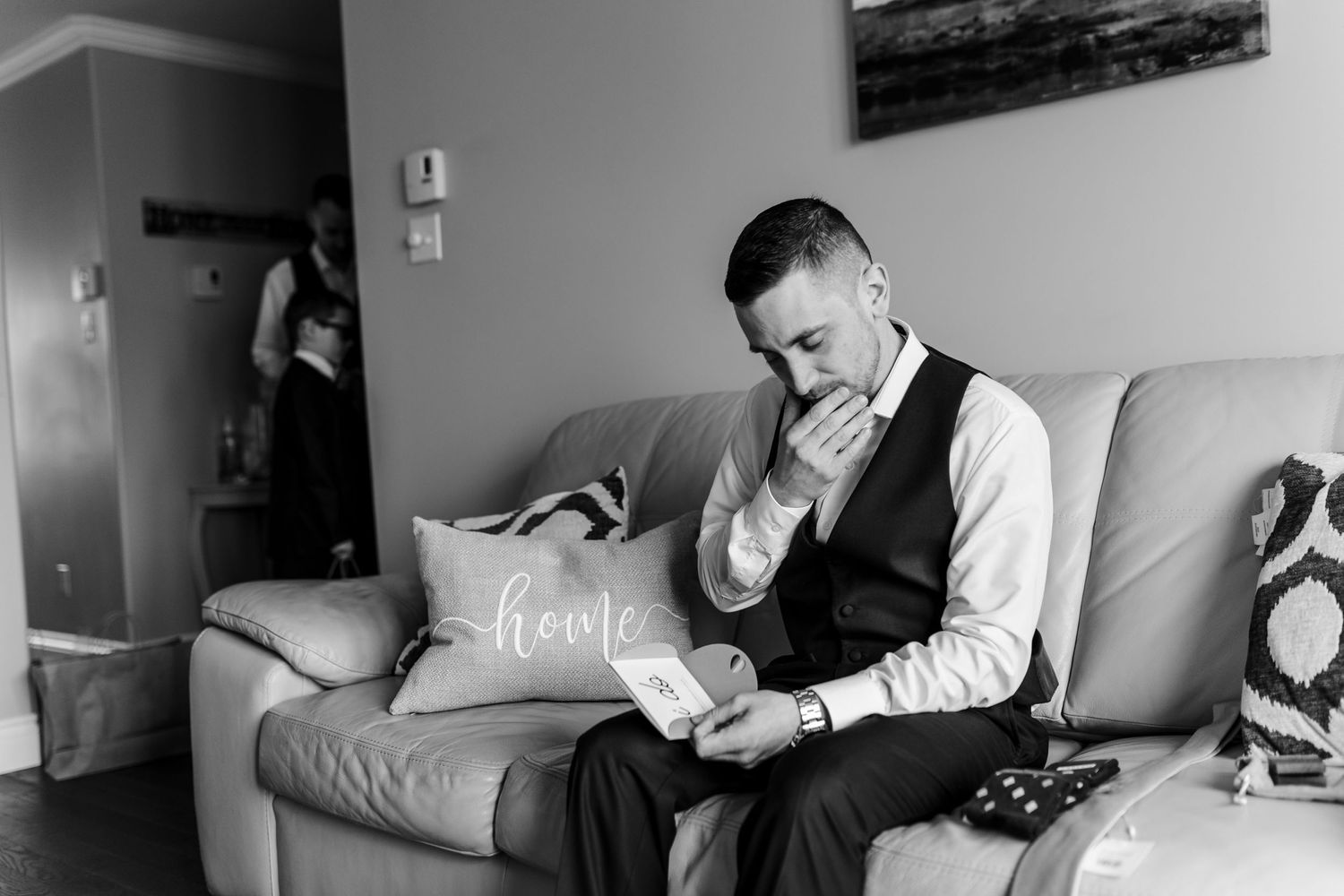 A black and white photo of someone reading while seated on a gray couch.