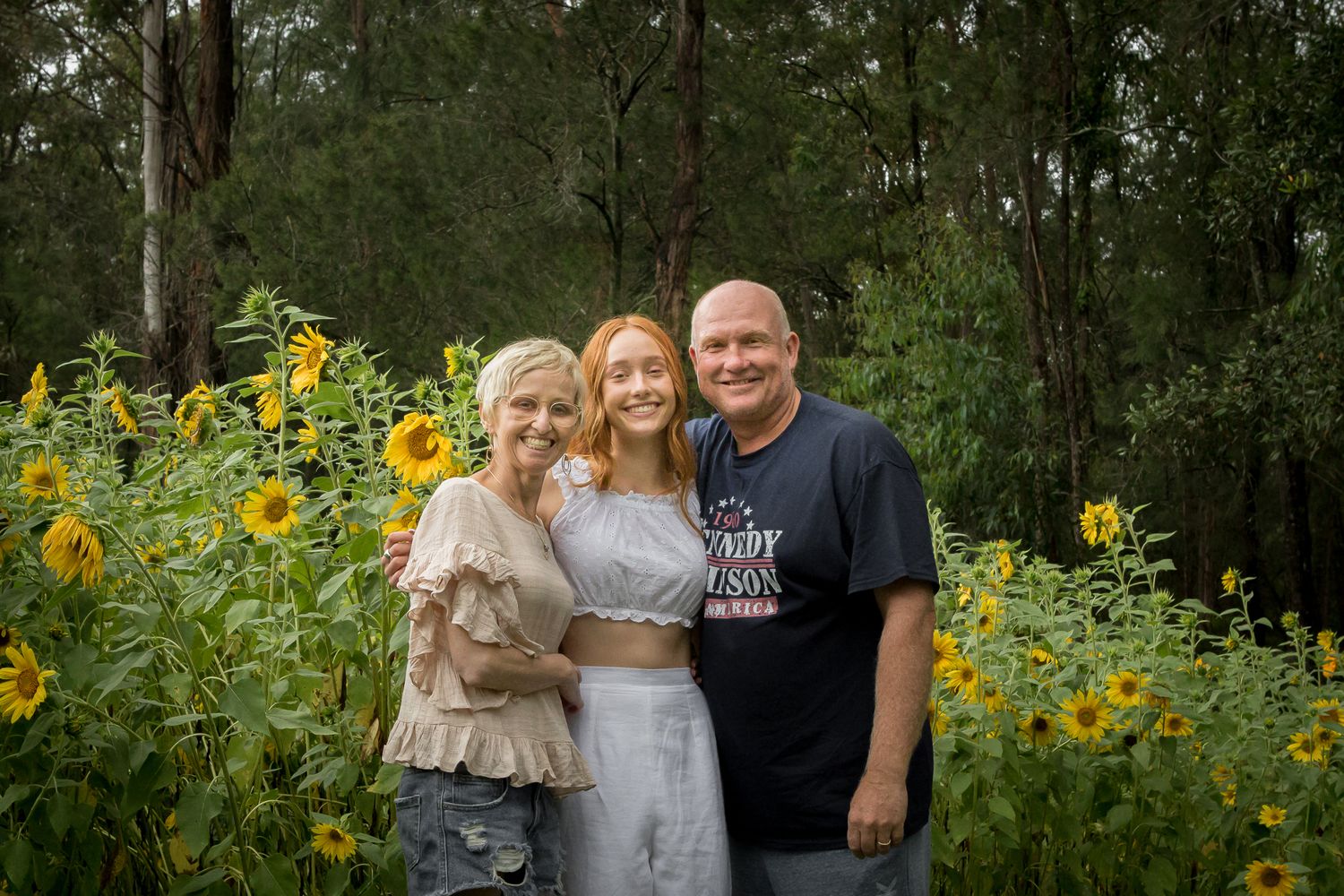 Family of three standing in amungst the sunflowers