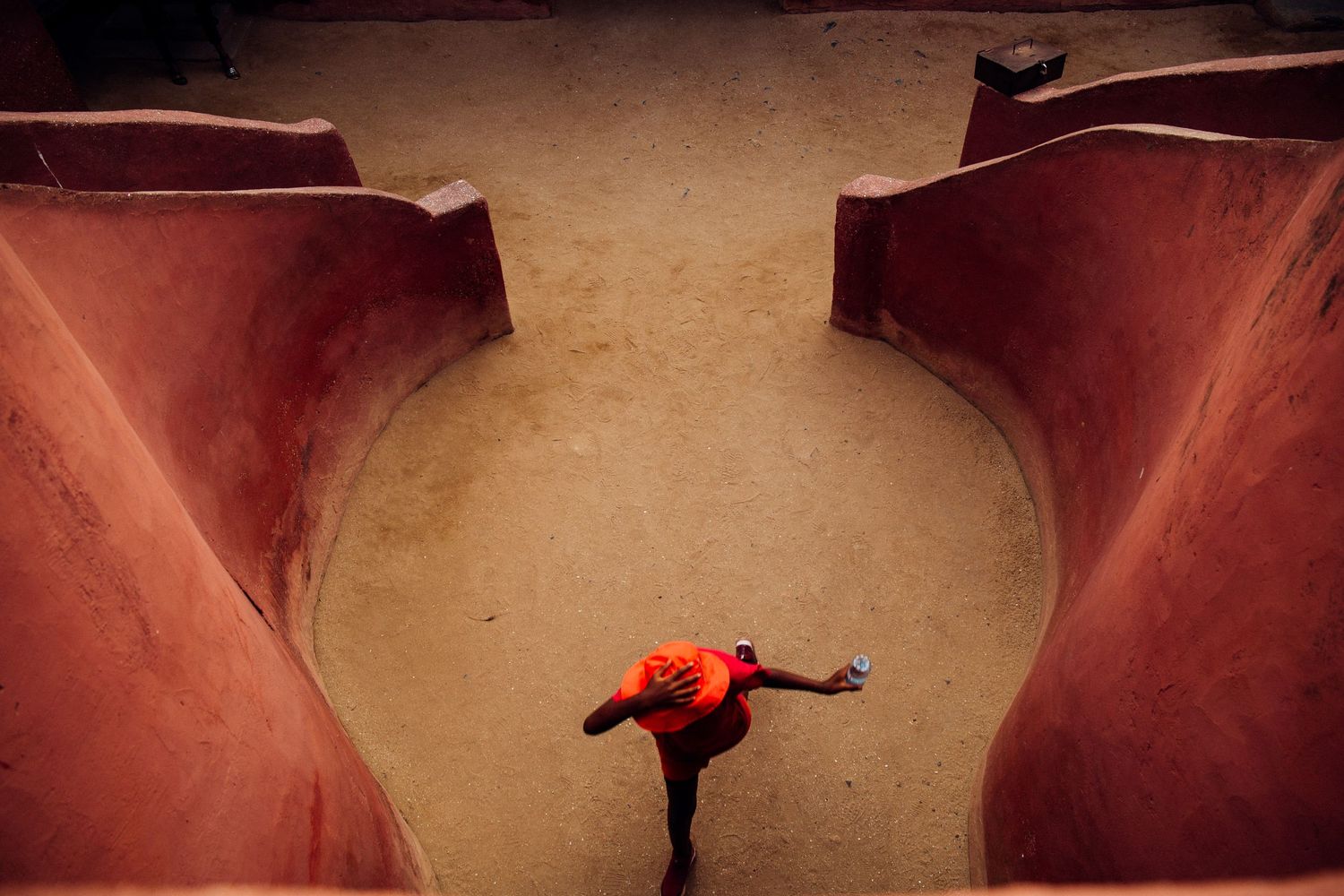 Person in red performs acrobatic pose between curved structures.