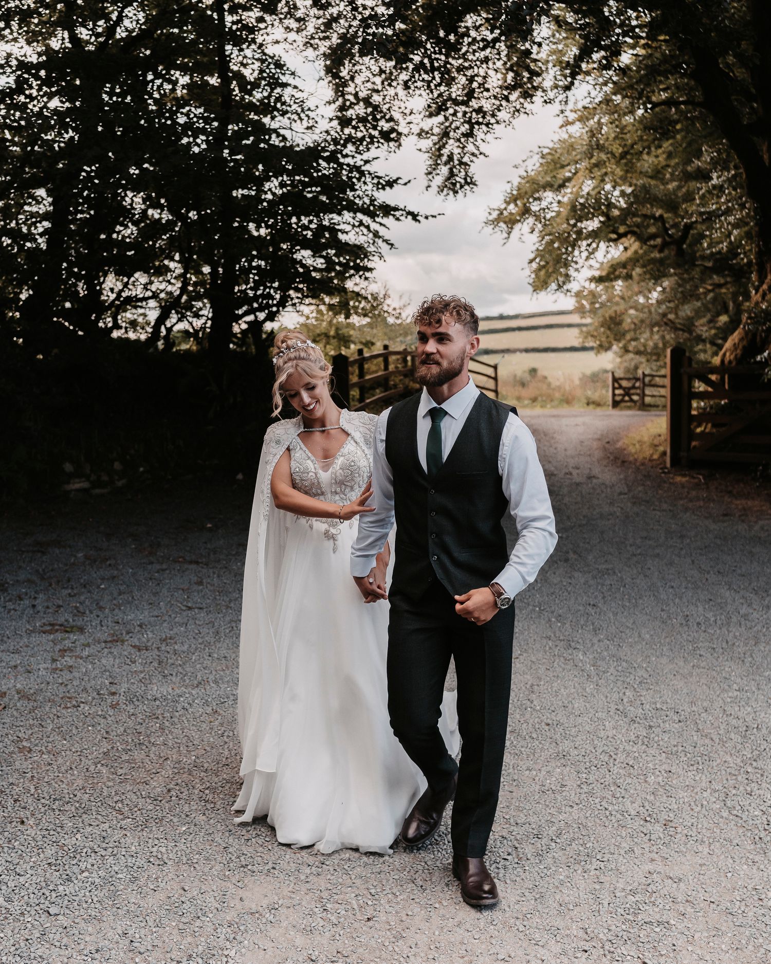 Wedding photo of bride and groom walking amongst the trees in Cornwall, UK just after they were married.